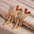 Dettaglio di orecchini a cuore con nappe, cristalli rossi e strass su sfondo di pietra - Perno in Argento 925 - Orecchini a Nappa a Cuore Rosso