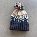 Detail showing high-quality geometric jacquard knitting and a colorful pom pom on top - One Size / Navy Blue