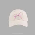 Detailed shot of pink bow embroidery on a beige cotton baseball cap with neat stitching - Bow Embroidered Baseball Cap Style / Beige