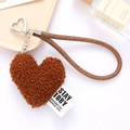 Close-up of brown plush heart keychain with woven lanyard and silver heart buckle - Coffee