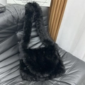 Chic black faux fur tote bag with wide shoulder strap placed on a luxury sofa - Black