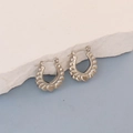 Detail of silver horseshoe earrings with embossed heart patterns on stone background - Silver Heart Embossed U-Shape