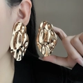 Close-up of chunky irregular geometric gold earrings with a polished hammered texture - E3773 Hammered Irregular Oval / Gold