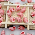 Detail of pink seashell ceramic beads on a bamboo tray for DIY jewelry making - Pink