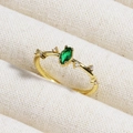 Detail of a gold emerald ring with an oval green gemstone and small clear zircons on the side - Oval Emerald With Small Diamonds (款式4)