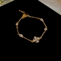 Dettaglio ravvicinato del bracciale a quadrifoglio dorato con zirconi e perle eleganti - Stile Quadrifoglio Zircone / Bracciale-Oro (Placcato Oro Vero)