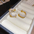 Macro shot of gold C-shaped earrings with pearls and rhinestones on beige velvet - Gold