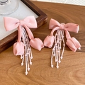Dettaglio di eleganti orecchini a fiocco in tessuto rosa con nappe di perline fini - Orecchini con perno in argento 925 / Rosa