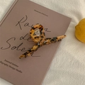 Detail of amber leopard print hair claw clip made of acetate on a lavender book - Dark Tortoise