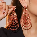 Eleganti orecchini lunghi con frange di strass rossi indossati da una modella - Orecchini a ciondolo grande a semicerchio rossi