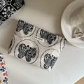 Detalle de un neceser de lino beige con elegantes bordados de mariposas negras - Bordado de Mariposa en Fondo Beige