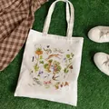 White canvas tote bag with hand-drawn strawberry and rabbit prints on grass background - C3 Forest Animals
