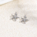 Macro shot of a pair of silver starfish charms made of copper for DIY jewelry making - Starfish / Silver