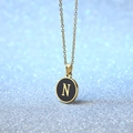 Golden necklace with round black pendant featuring a gold letter N and a shiny finish - Letter N