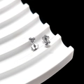 Detailed macro view of silver triple-bead stud earrings with flower backing on a white stand - Three Beads