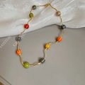 Detail of colorful ceramic beaded necklace with wavy golden chain and textured beads - Colorful