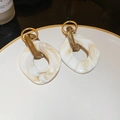 Nahaufnahme der Marmor-Harz-Ohrringe mit goldenen Ringen auf einem weißen Teller - Kaffee-Weiß Marmor