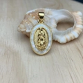 Macro shot of oval gold Guadalupe pendant with mother of pearl inlay on seashell - White
