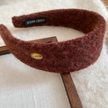 Close-up of caramel fleece headband with gold Korea metal tag on a wooden frame - Brown