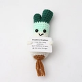 Detailed knit of a crochet positive scallion doll holding an encouraging message card - Scallion with Brown Roots