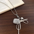 Dettaglio della collana in lega d'argento con sfera a rete e fiocco in nastro bianco su libro - 19# Collana Di Perle Argentate Con Ciondolo A Sfera In Maglia Con Fiocco Bianco (HN9034)