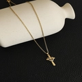 Dettaglio della collana con pendente a croce cuore dorato e zirconi su vaso di ceramica - Oro-Stile D-Cuore Croce