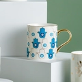 White ceramic mug with gold handle and blue Hamsa Evil Eye pattern in a modern setup - Alternating Hamsa Eye Gold Style (CF0164)