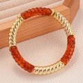 Macro del bracciale geometrico in metallo dorato e acrilico ambrato in scatola portagioie - Caffè Scuro