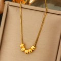 Elegante goldene Halskette mit strukturierten Perlen auf einer champagnerfarbenen Box - Jx069