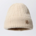 Close-up of beige cable knit beanie featuring a gold rhinestone M metal emblem - One Size / Beige (Round M)