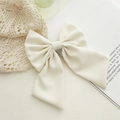 Elegant cream-white fabric bow hair clip shown on a minimalist vintage book background - Off White