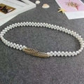 Elegant white pearl elastic waist chain with golden leaf buckle on a grey background - Leaves