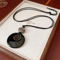 Détail du collier géométrique avec anneau noir et perle marbrée sur plateau bois - Collier-Noir