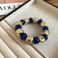 Gros plan sur le bracelet élastique avec perles carrées dorées et perles acryliques bleues - Bleu
