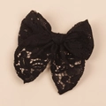 Detailed view of a black hollow lace bow hair clip for children on beige background - Black