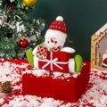 Kerstman sneeuwpop pluche figuur met rode gebreide muts en sjaal op een feestelijke doos - Sneeuwpop