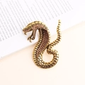 Elegante spilla a serpente dorata con strass scintillanti su un libro bianco - Arancione