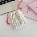Close-up of cream quilted drawstring pouch with pink cords on a minimalist desk - Baby Cotton White / Small