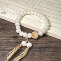 Macro detail of cat paw charm and white beads on a Chinese style braided bracelet - Apple Beads + Cat Paw