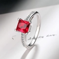 Detail of princess cut red stone ring with cubic zirconia on polished silver band - Red Zirconia