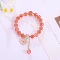 Details von rosa Erdbeerkristall-Armband mit Gänseblümchen-Anhänger und Goldquasten - Rosenrot