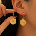 Elegant gold coin earrings with starburst engraving and zircon on female model - Stainless Steel/Zirconia / Compass Star Round Disc - Gold