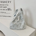 Detail of light blue floral canvas handbag with delicate white lace trim and knot handle - Blue