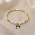 Detailed shot of gold beads, white pearls, and a black horn pendant on a silk fabric - Black Celestial Moon