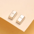 Primer plano de pendientes plateados de acero en forma de lingote con grabado GOLD - Color Acero
