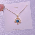 Dettaglio del ciondolo a forma di pianeta vintage con pietra blu e cristalli rossi - Croce Svuotata Stellata (XK0041)