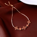 Detail of adjustable 18K gold plated flower bracelet with orange gems on red velvet - Gold-Orange