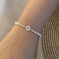 Detail of beaded alphabet bracelet with letter R on wrist against woven texture - Letter R Style (R)