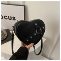 Detail of a heart-shaped black leather bag with silver rivets and metal buckle hardware - Black