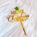 Close-up of golden acrylic Merry Christmas cake topper with green glitter star detail - Five-pointed Star Merry Christmas
